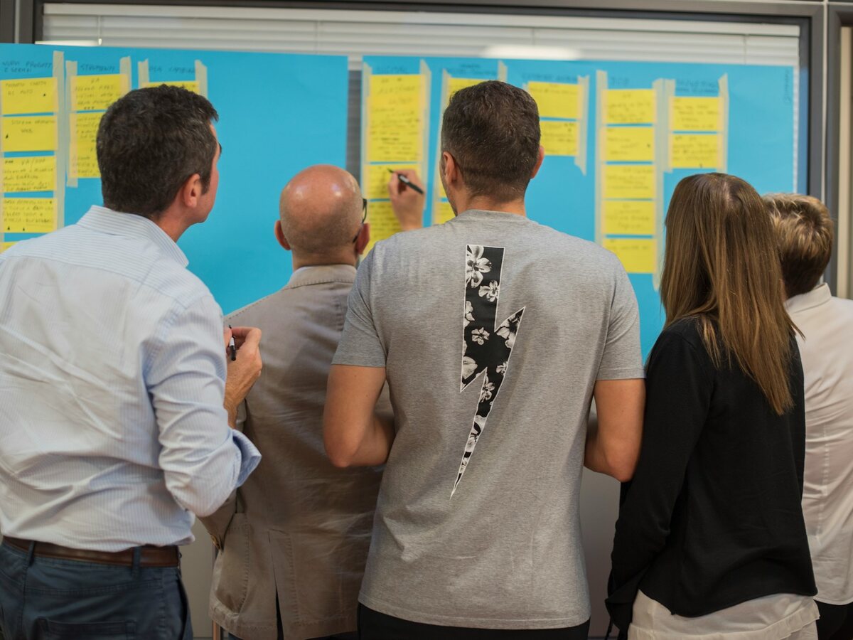 Four colleagues standing at a wall of sticky notes, arranging and discussing them together